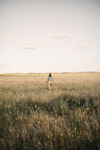 Woman walking amidst plants at agricultural field