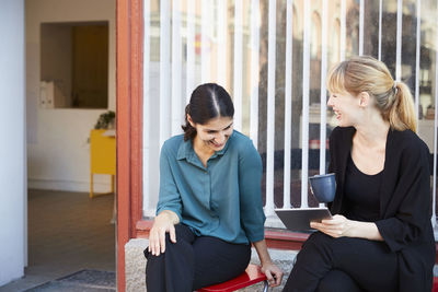 Smiling mid adult businesswomen sitting outside office