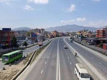 Vehicles on road against sky in city