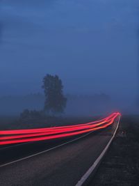 Light trails on road against sky at dusk