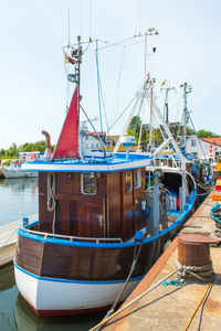 Boats moored at harbor against sky