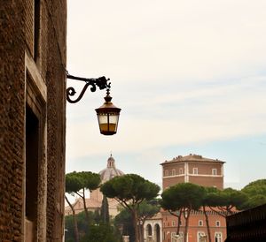 Low angle view of street light by building against sky