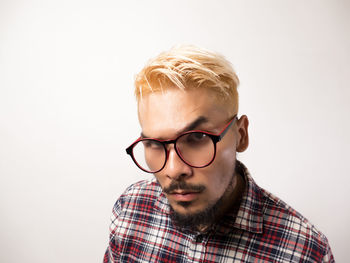 Portrait of young man wearing eyeglasses against white background