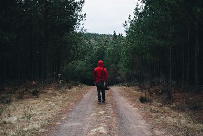 Rear view of woman walking on dirt road