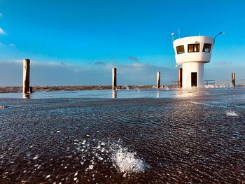 Lighthouse by sea against blue sky