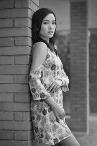 Portrait of woman standing against brick wall