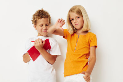 Portrait of smiling girl with brother against white background