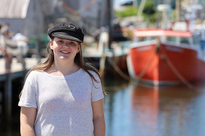 Portrait of smiling young woman standing in water with boats blurred in background