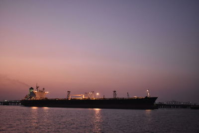 Commercial dock by sea against sky during sunset