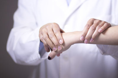 Midsection of doctor examining patient hand in hospital