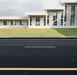 Empty road by building against sky