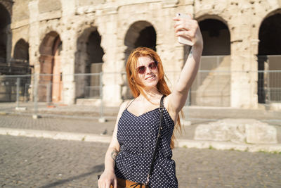 Cheerful tourist taking selfie on street