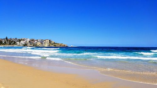 Scenic view of beach against clear blue sky