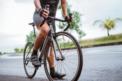 Low section of man standing with bicycle on road