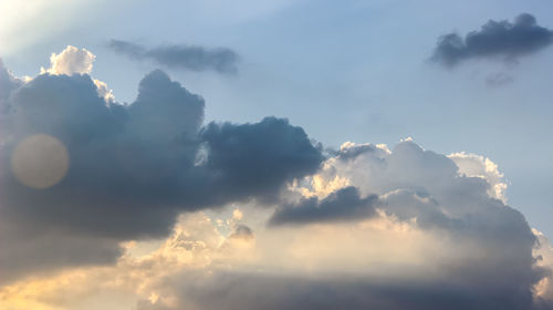 Low angle view of sunlight streaming through clouds