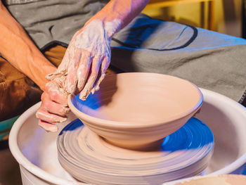 Cropped hand of potter making pot using pottery wheel in workshop