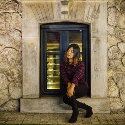 Portrait of woman sitting at entrance of building