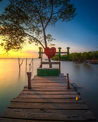Pier over lake against sky during sunset