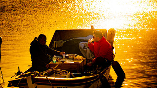 People standing on boat against sea during sunset