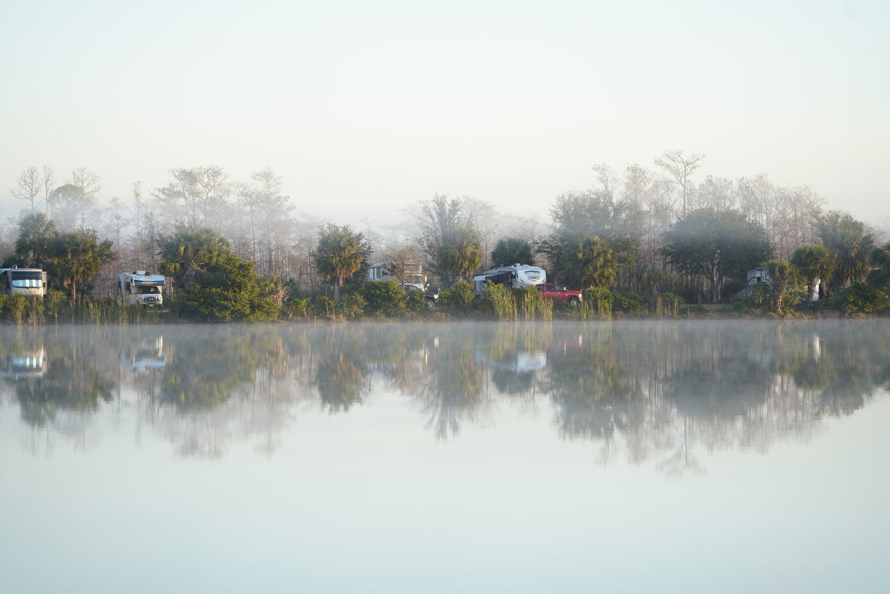 REFLECTION OF TREES IN LAKE AGAINST CLEAR SKY