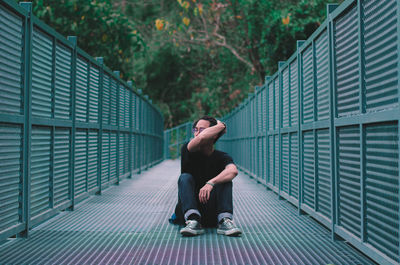 Side view of man sitting on footpath