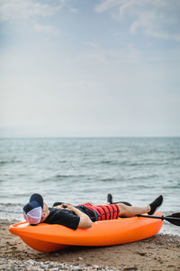 Man taking a nap on kayak on the beach during summer vacation