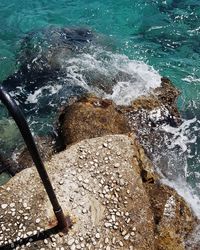 High angle view of sea waves splashing on rocks