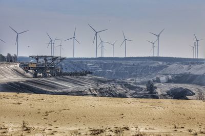 Windmills on landscape against sky