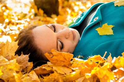 Portrait of boy lying down on leaves during autumn