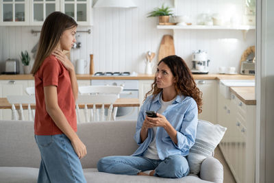 Young woman using mobile phone while sitting at home