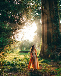 Woman standing on land against tree in forest