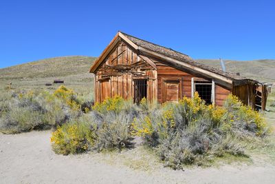 Old house on field against clear blue sky