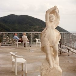 Statue of man standing by railing against sky