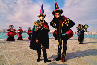 Full length of disguised people standing against sky in venice