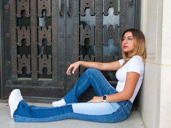 Portrait of young woman sitting in front of door 