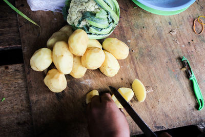 High angle view of hand holding fruits on cutting board