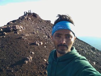 Portrait of man on rock against sky
