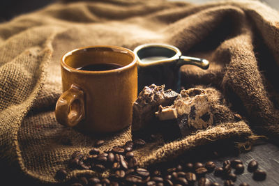 Close-up of coffee cup and cake with roasted beans on sack