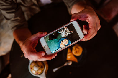 Cropped hands of woman photographing food with smart phone