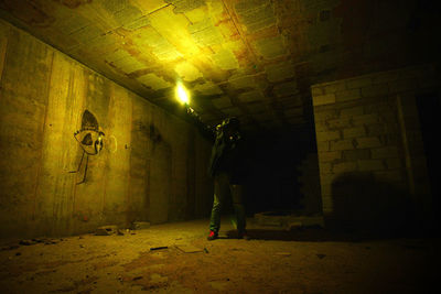 Man standing by wall in illuminated room