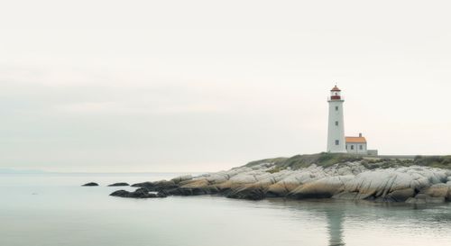 Lighthouse by sea against sky