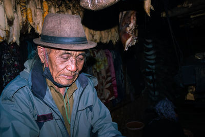 Senior man wearing hat while sitting at market stall
