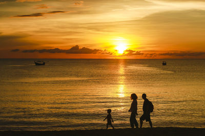 Silhouette of sunset over the sea with a family walking on the beach at khao lak  thailand.