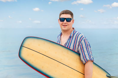 Portrait of young woman wearing sunglasses against sea