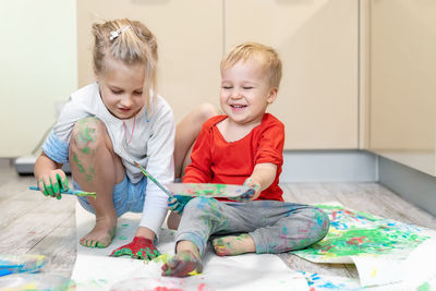 Siblings playing with watercolor paints at home