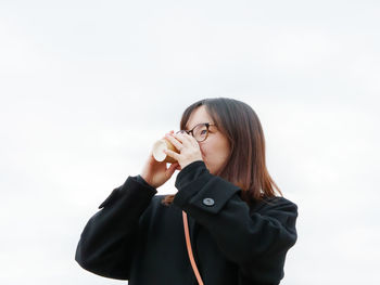 Portrait of young woman standing against white background