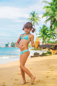 Girl applying moisturizer on stomach at beach