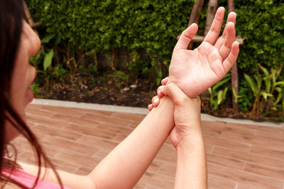 Midsection of woman with wrist pain against plants