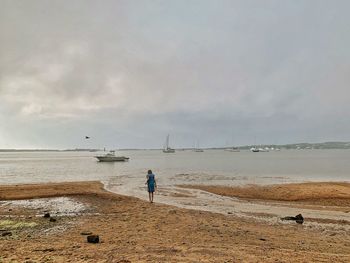 Rear view of girl at beach against sky