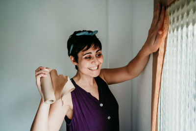 Portrait of a smiling young woman standing against wall